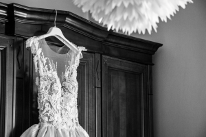A wedding gown hangs on the outside of a cupboard.