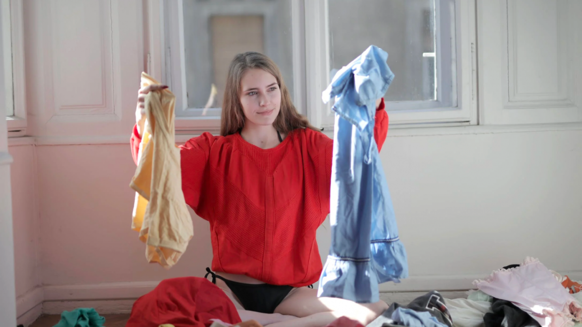 A woman sorts through piles of laundry after cleaning.