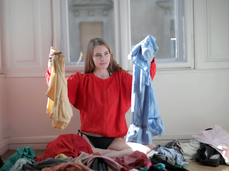 A woman sorts through piles of laundry after cleaning.